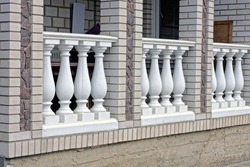 gray brick wall of a private house with a row of white concrete columns on the street