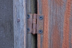 one brown small rusty iron door hinge on gray red wooden door boards