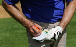 Golfer keeping score on scorecard