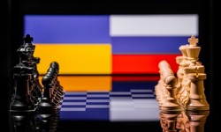Conceptual image of war between Russia and Ukraine using chess pieces and national flags on a reflective background