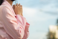 A girl wearing a pink coat is standing praying to God asking God's blessing to bring her lover back to her. concept of believe and the power of faith in God and blessings