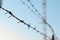 Razor wire. Rusty metal barbered wire on a border check point. Wire fence around military or infrastructure objects. Close up of a prison barbed wire near jail or concentration cam