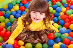 Happy little girl in group colourful ball.