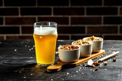 Bowl of nuts and beer on wooden table, set of peanuts with different flavors, Snacks for beer. banner, menu, recipe,