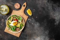 Keto diet plate quinoa, avocado, egg, tomatoes, spinach and sunflower seeds on dark background. Healthy food, ketogenic diet, diet lunch concept, place for text, top view.