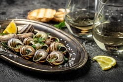 Baked snails with butter and spice on dark background. Snails baked with sauce, Bourgogne Escargot Snails. gourmet food. concept of french cuisine, Long banner format. top view.