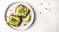 Healthy avocado toasts with rye bread, sliced avocado, cheese, pumpkin, nut and sesame for breakfast or lunch. Vegetarian food. Vegan menu. Long banner format. top view.