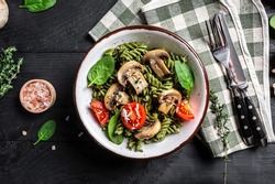 Mushroom and Spinach Pasta in a Bowl, Vegan Food on dark background. Vegan or gluten free diet. banner, menu recipe place for text, top view.