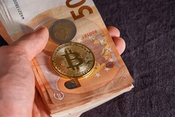 Man's hand with bitcoin and 50 fifty euros of backgrounds bills banknotes