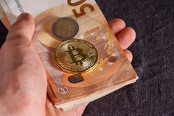 Man's hand with bitcoin and 50 fifty euros of backgrounds bills banknotes