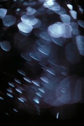 Abstract dark background with glowing blue particles. Beautiful blur and bokeh 