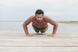 Shirtless Athletic Army in Camouflage Pants Doing Push Up Exercise at the beach