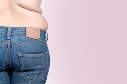 back view. asian fat women has overweight. she shows excess fat of the waist. isolated on violet background. she wants lose weight. concept of surgery and subcutaneous fat breakdown.