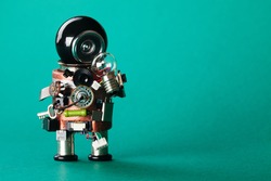 Creative idea concept. Robot looking at light bulb. retro style toy character with funny black helmet head. Copy space, green background