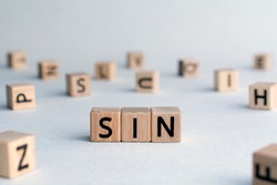 sin - word from wooden blocks with letters, to break a religious or moral law concept, random letters around, top view on wooden background