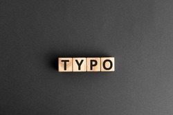 Typo - word from wooden blocks with letters, a typographical error typo concept, random letters around, top view gray background