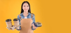 pretty asian female smile coffee freelancer own coffee bar shop hold coffee paper cup and payment with a credit card through terminal money swiping a credit card in her own shop yellow background.