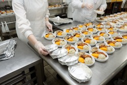 Female cooks are wrapping airline food in foil, commercial kitchen, reality shot