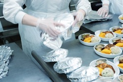 Chef is wrapping airline food in foil, professional kitchen, toned image
