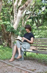 Woman sitting on old bench,reading book,hobby on holiday,in a park
