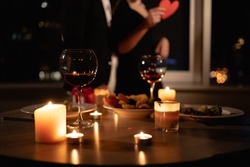 romantic dinner setting, red wine in glasses and candles, date for two, Valentine's Day evening, burning candles on the table, close-up