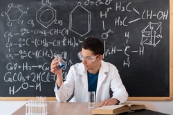 Chemist scientist examines a flask with reagent. arab student mixes chemicals in a flask. focused teacher giving chemistry lesson, muslim laboratory chemist showing new experiment of science class