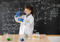 young girl student chemist in a white coat makes a chemical experiment in a chemistry lesson, back to school female career concept