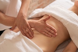 relaxing massage and body shaping massage, lymphatic drainage, manual and aesthetic procedures, hands massaging belly in the spa salon