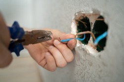 man works with electrical wires using tools, fixing socket at home, male household work with electricity, pliers and wire cutters in man's hands, electrician working with wire