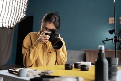 Professional photographer taking photo of cosmetic products on desktop, using camera and natural light Indoors. Blogging, profession and people concept