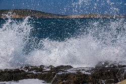 Big wave close up. Rocky beach in St Paul's Bay, Malta at sunny day. Beautiful stormy blue mediterranean sea. Selective focus.