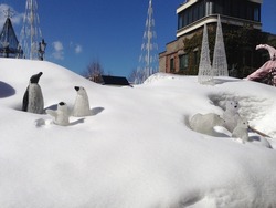 Three penguin and polar bear statue on snow and blue sky background
