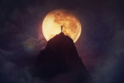 Self overcome concept as a person raising hands up on the top of a mountain over full moon night background. Conquering obstacles, success achieving. Road to win, freedom symbol.