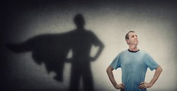 Confident and optimistic middle aged man, hands on hips showing chest, brave gesture, like a powerful superhero casting shadow on the wall. Inner strength, motivation and ambitions, leadership concept