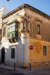 Corner house constructed of limestone with statue of Jesus, Mosta, Malta