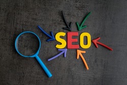 SEO, Search Engine Optimization ranking concept, magnifying glass with arrows pointing to alphabets abbreviation SEO at the center of cement wall chalkboard, the idea of promote traffic to website.