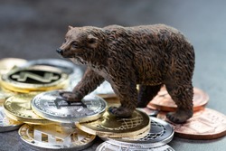 Bearish market concept, price down or falling demand collapse of crypto currency, bear figure standing on various of cryptocurrency physical coins, Bitcoin, Ripple, ZCash, Litecoins, Ethereum.