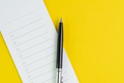 Important business checklist, planning for shopping reminder or project priority task list, black pen on small notepad with checkbox on solid yellow background with copy space.