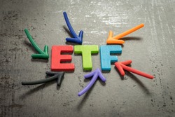 ETF, exchange-traded fund an investment fund traded on stock exchanges concept, multi color arrows pointing to the word ETF at the center of black cement chalkboard wall.