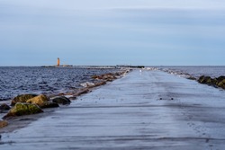 Mangalsala or Eastern pier during winter storm with a bright orange lighthouse at the end. One of the pier in the city of Riga, Latvia where river Daugava flows into the Baltic Sea.