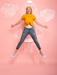 Girl jumps on pink background ready to fly like a rocket. Concept of freedom, energy and vitality