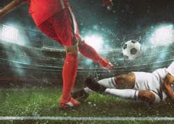 Soccer scene at the stadium with player in a red uniform kicking the ball and opponent in tackle to defend