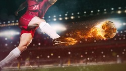 Close up of a soccer scene at night match with player in a red uniform kicking a fiery ball with power