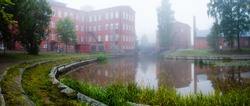 Forssa Finland, the old spinning mill of red brick on a foggy day and Loimijoki river