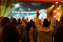 Worship includes music and numerous people lifting their hands in praise to God on stage 