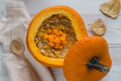 oatmeal, porridge with pumpkin inside bright big orange squash, autumn breakfast, soft selective focus, top view from above