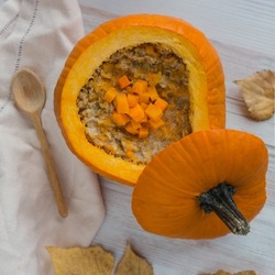 oatmeal, porridge with pumpkin inside bright big orange squash, autumn breakfast, soft selective focus, top view from above, square