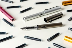 Ink pens and ink cartridges are scattered on the table.