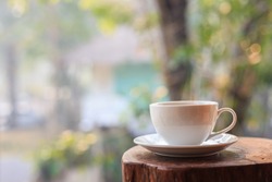 Close up white coffee cup on table in garden with blur light bokeh