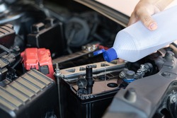 A man add water to distilled the car battery maintenance and inspections for extended service life of car

